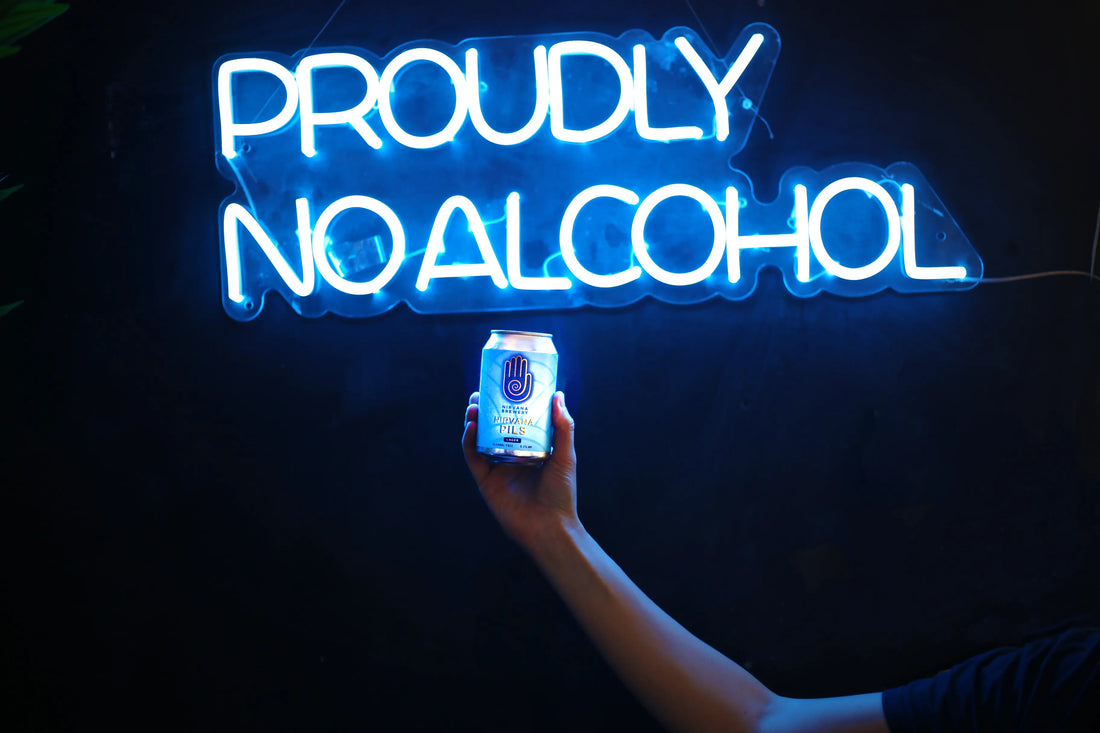 the stigma of brewing alcohol free beer blog image of an arm holding a Nirvana Pils Beer Can and a neon sign in the background saying "Proudly no alcohol"