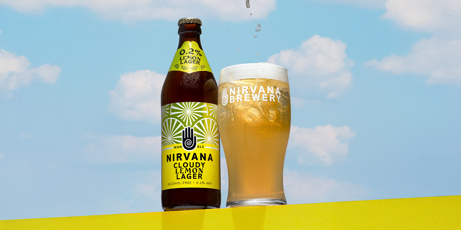 Nirvana Brewery Cloudy Lemon Lager and beer glass on a yellow wall and cloudy backdrop