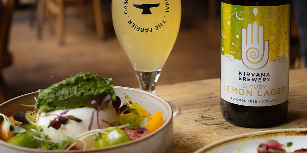 The benefits of alcohol free beer blog image with a bottle of nirvana cloudy lemon lager next to a delicious looking salad and a farrier beer glass holding nirvana's cloudy lemon lager